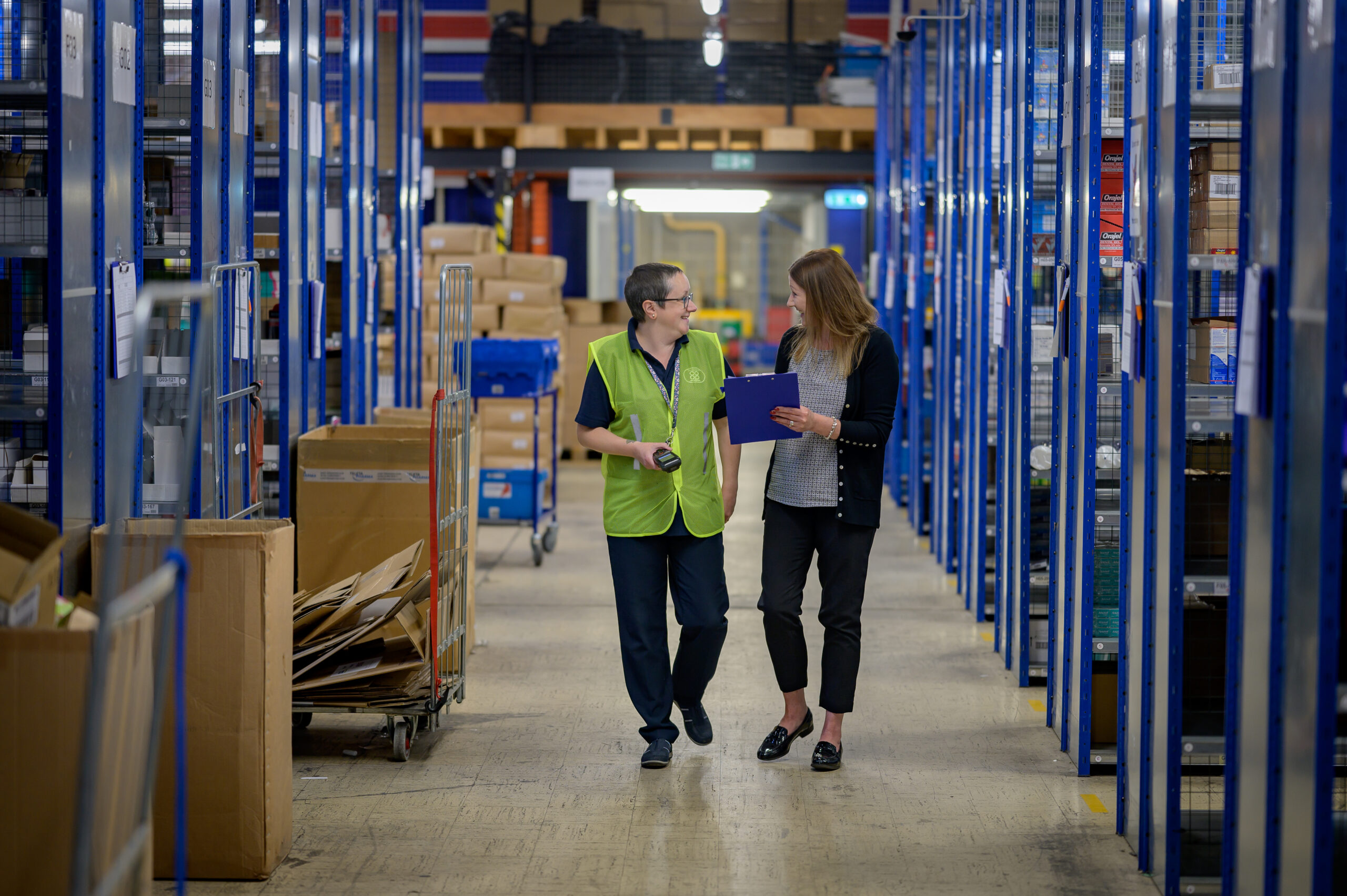 Two people at work in a warehouse having a conversation