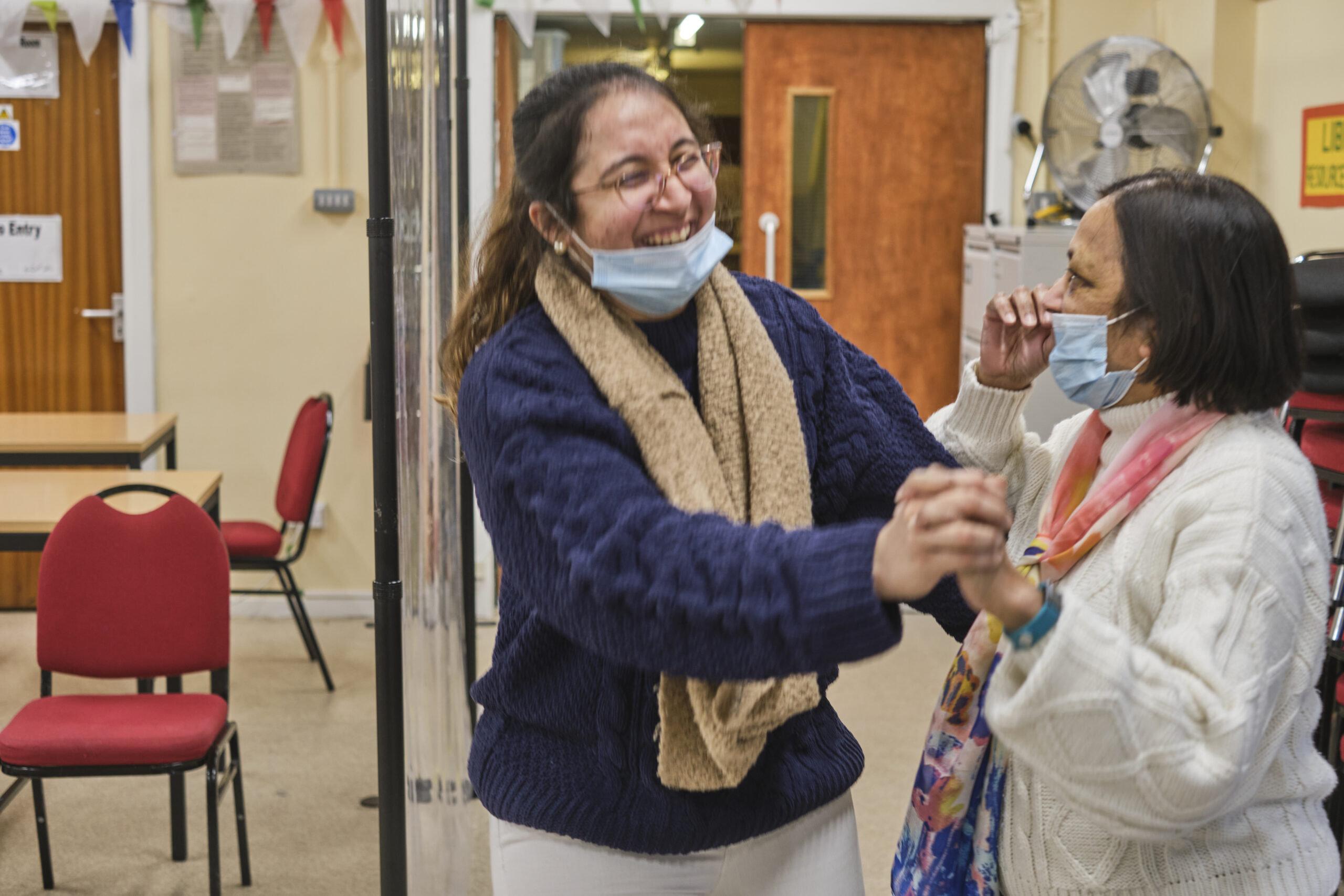 Two women in a medical setting are holding hands and dancing