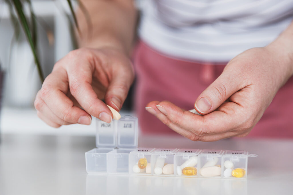 Someone is placing medication into a pill tray