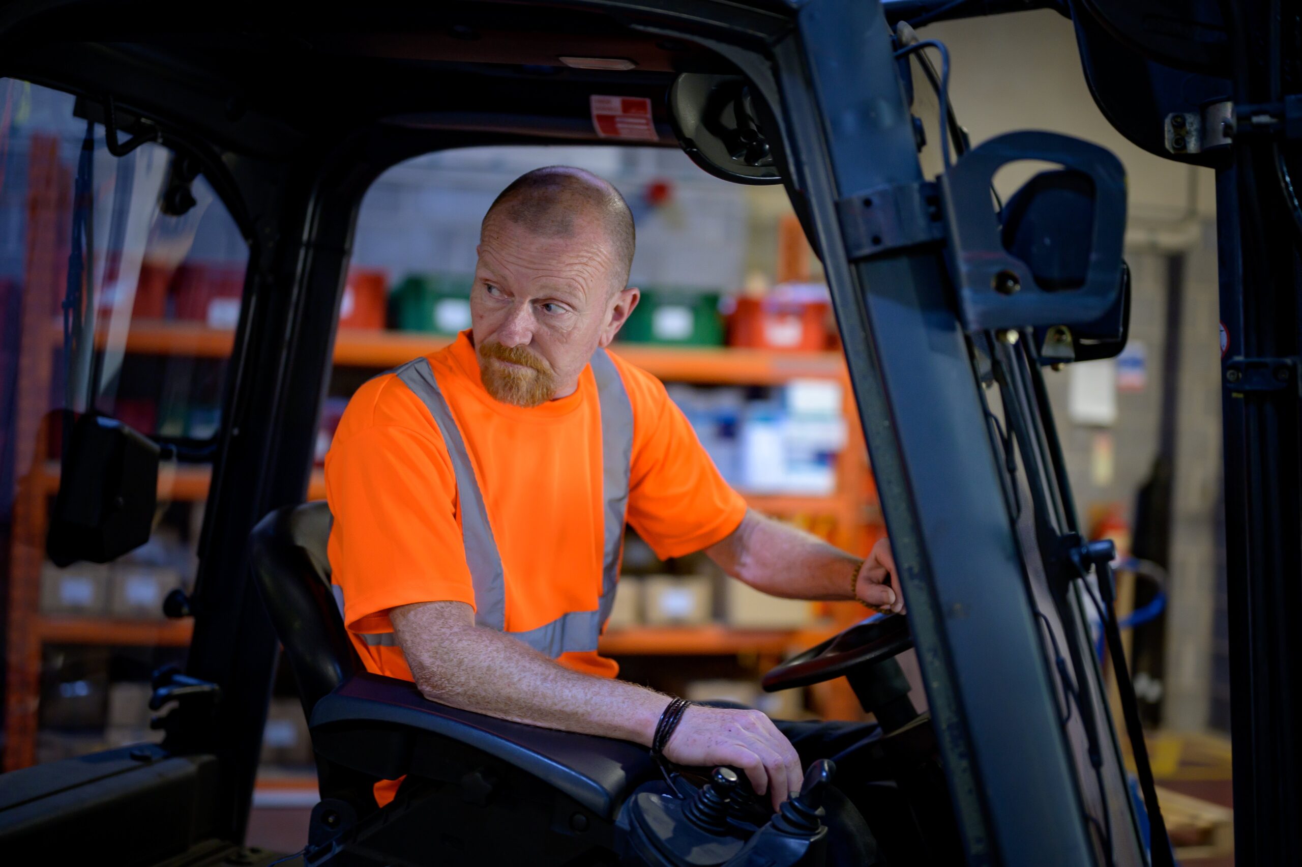 A man wearing a high vis vest is driving a fork lift