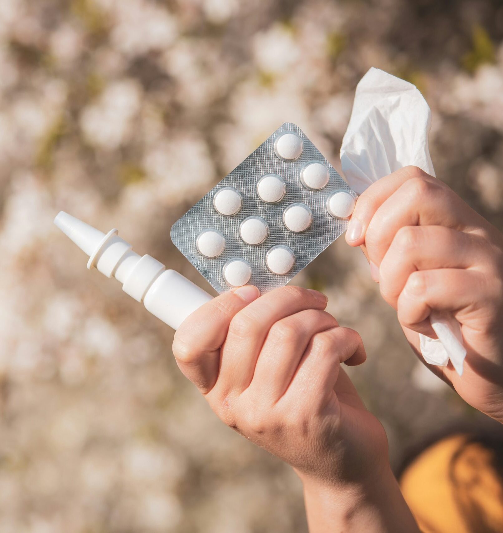 Someone holding a pill packet and nasal spray