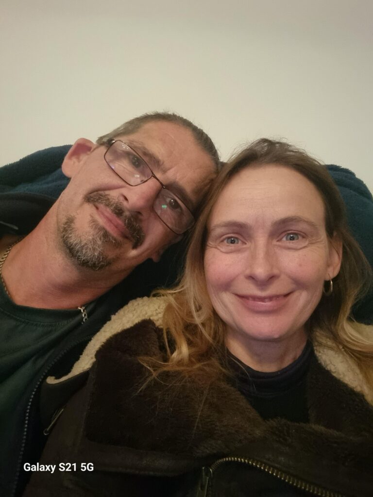 A man and woman sit together smiling. 