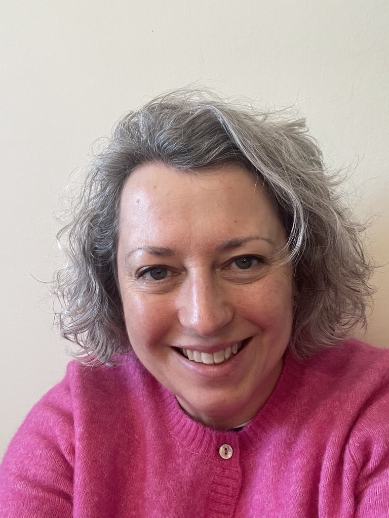 Emma is smiling and wearing a pink cardigan