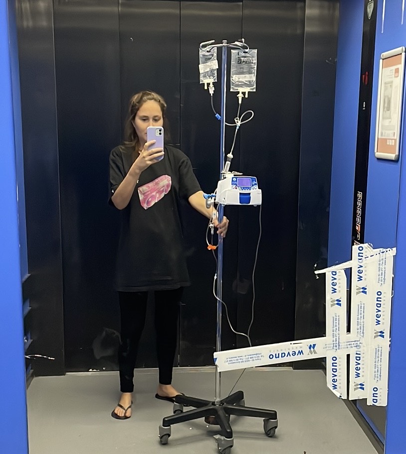 Francesca standing in a lift attached to her IV drip stand