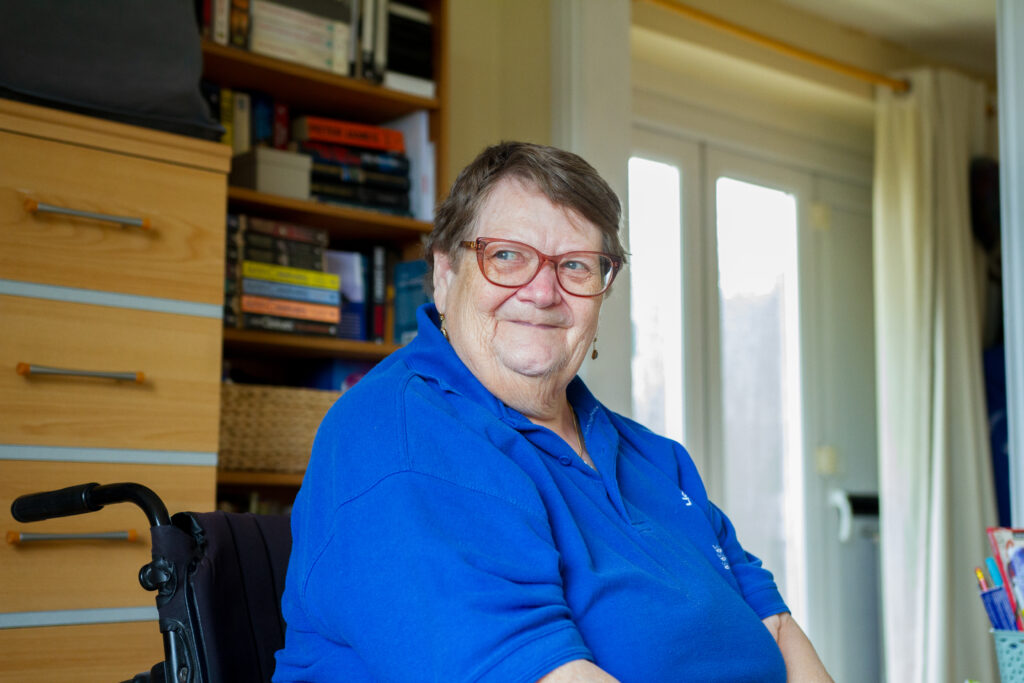 A person wearing a blue top and glasses smiling