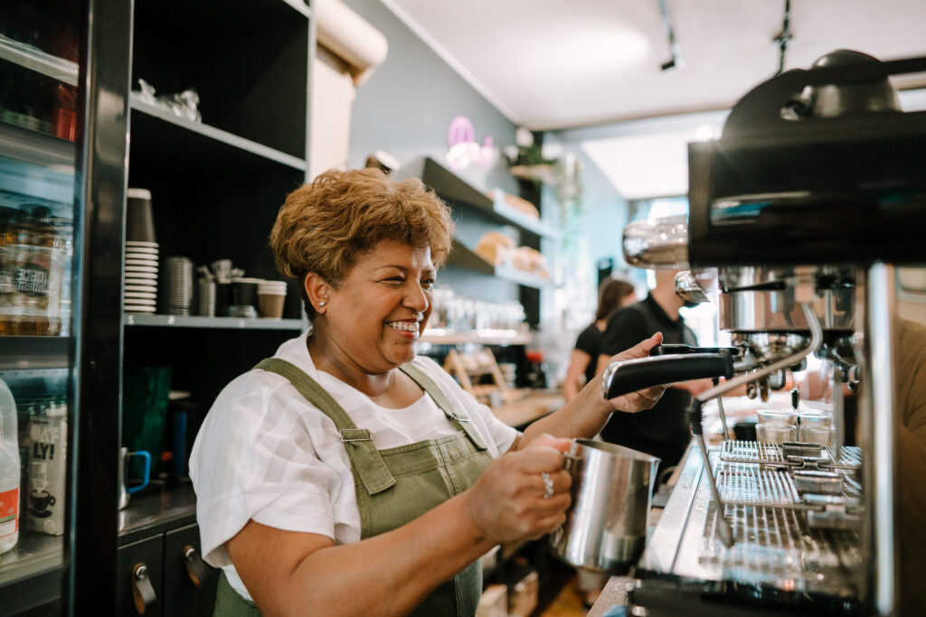 A female barista steaming milk at a coffee machine