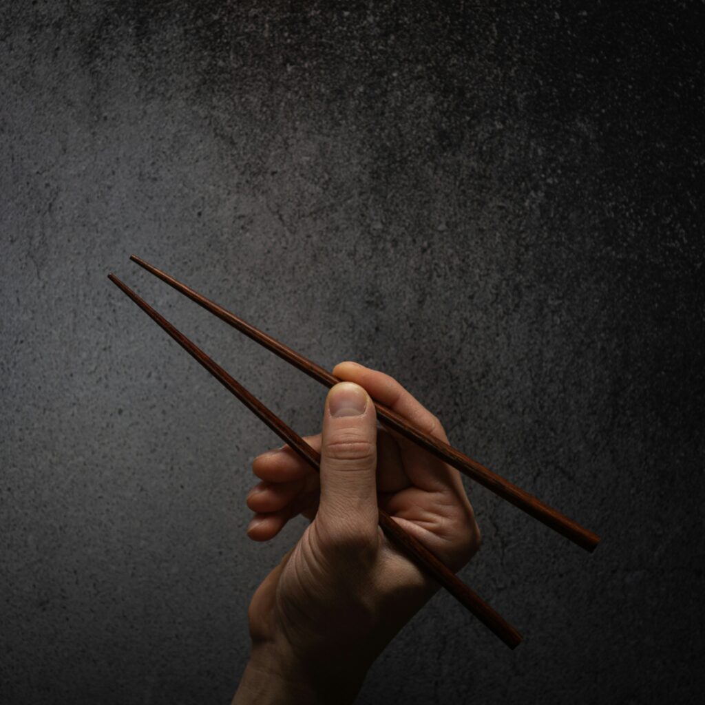 A hand holding chopstix